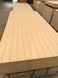Stack of grooved plywood sheets in warehouse, plywood panels with V-grooves for wall lining