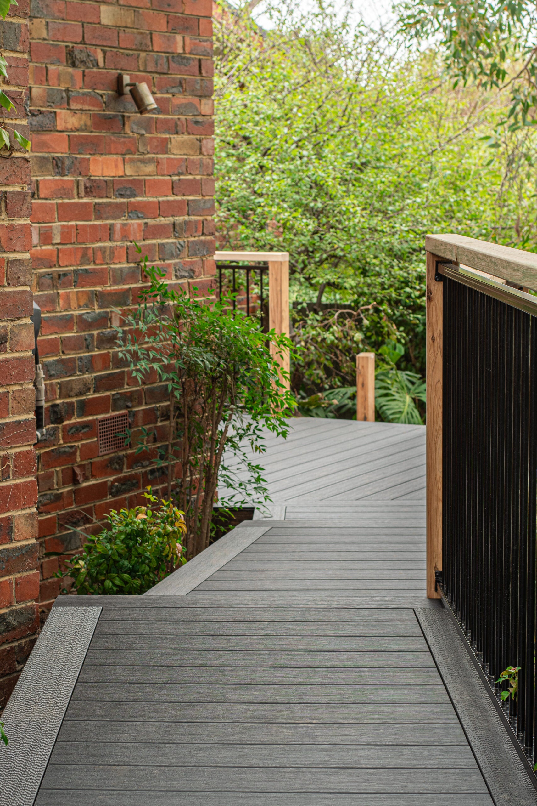 Grey WoodEvo HOME composite decking walkway beside a brick home